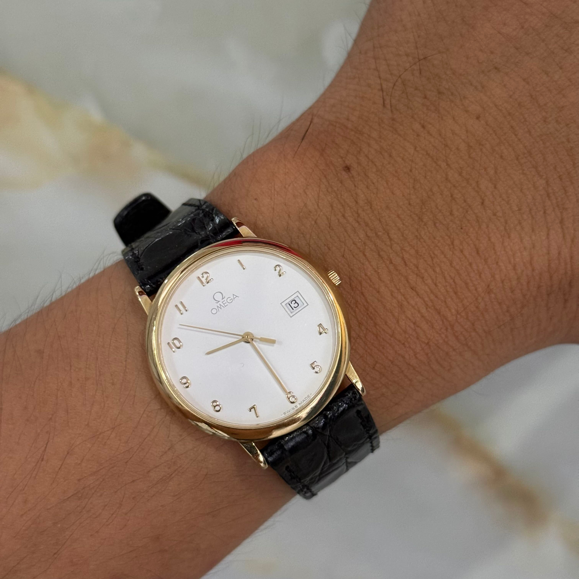 Buyer wearing a gold Omega dress watch on a black alligator strap