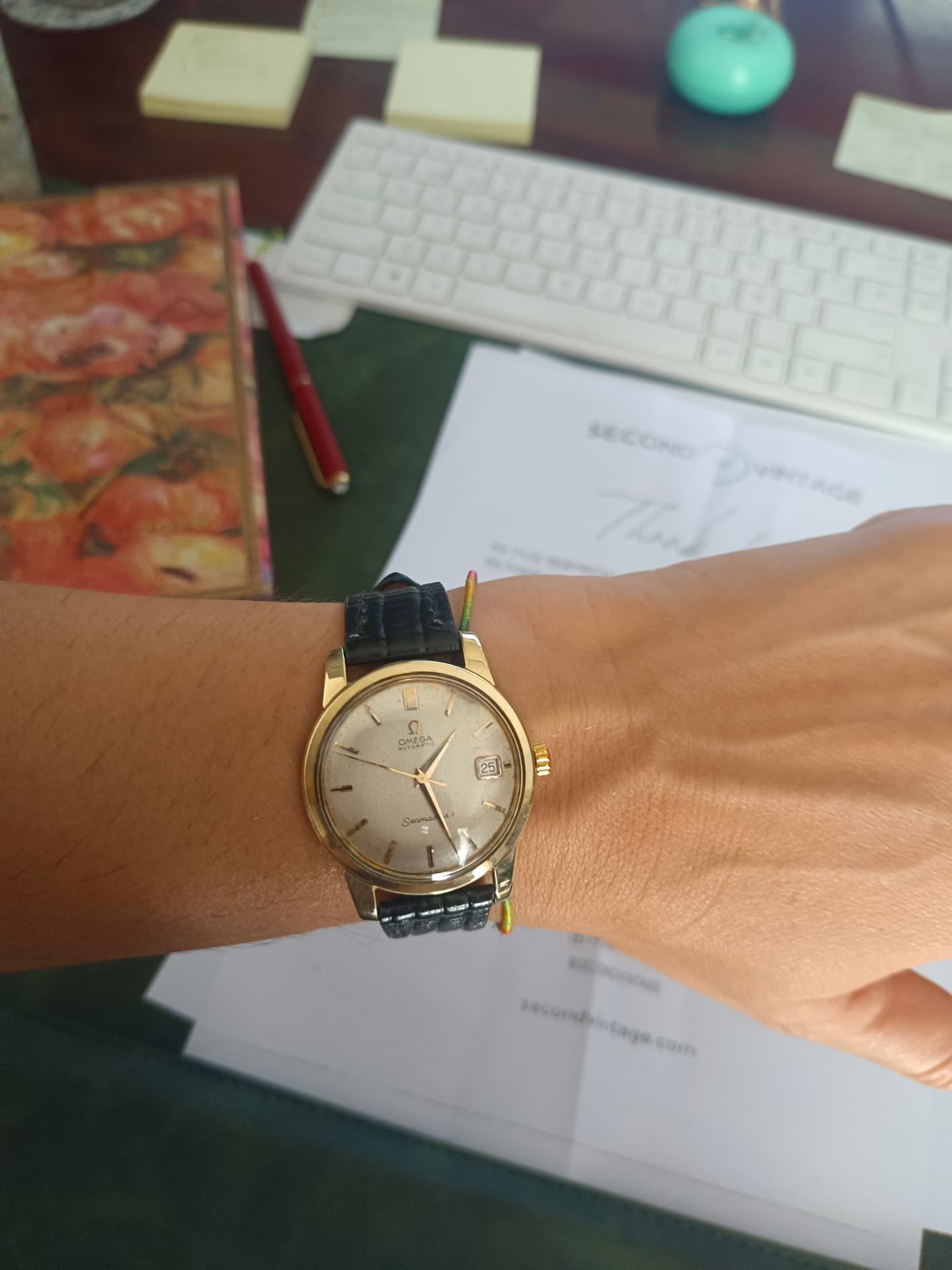 Buyer wearing a gold vintage Omega Seamaster at their desk with Second Vintage paperwork