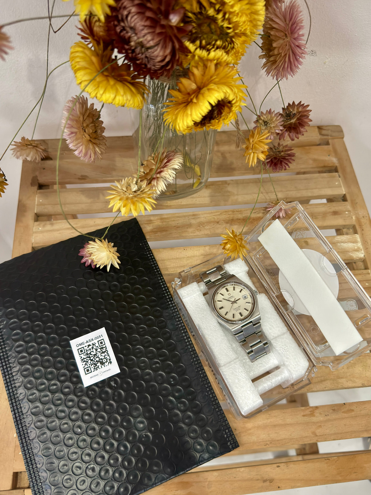 Omega Seamaster in its Second Vintage travel case on a table with dried flowers